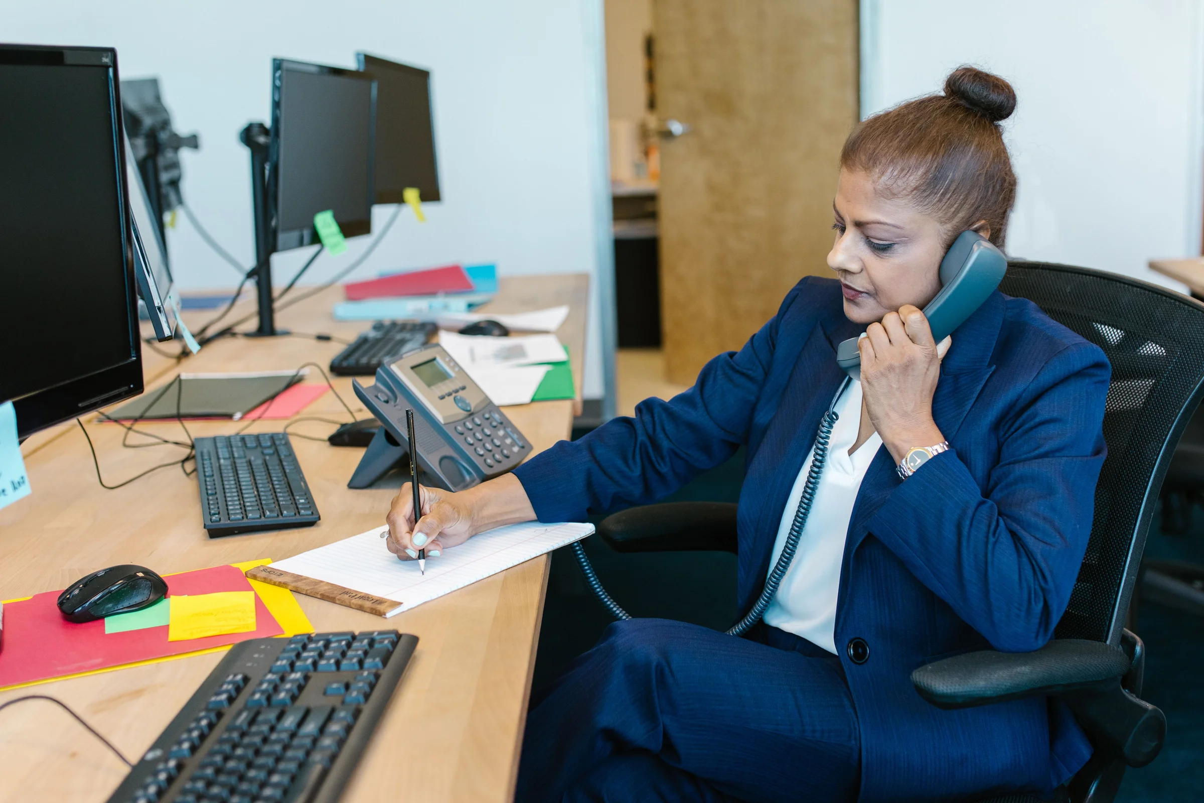 Hospital accounts staff at a billing desk, on the phone with a patient about their bill