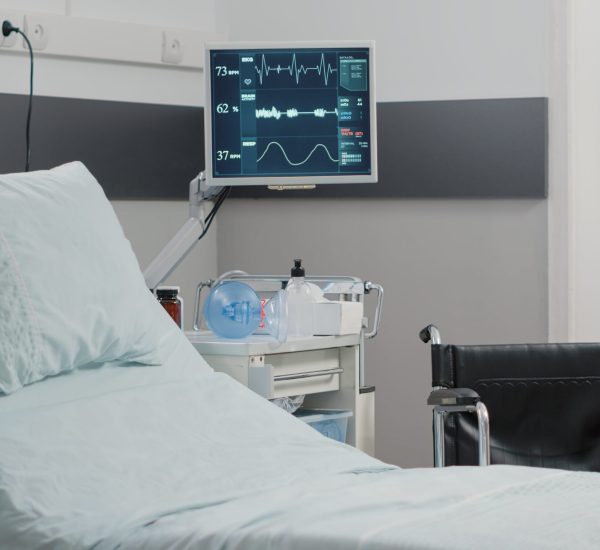 Empty hospital ward with heart rate monitor and bed Empty hospital ward with heart rate monitor and bed for healthcare and recovery. Nobody in emergency room with medical equipment for intensive care patient. Reanimation room with tools