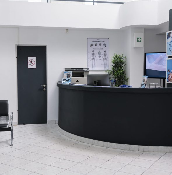 Nobody in waiting room with front desk reception and wall screen tv with promotional offer Nobody in waiting room with front desk reception and wall screen tv with promotional offer in private practice hopital. Waiting area for patients with doctor appointments in modern healthcare clinic.