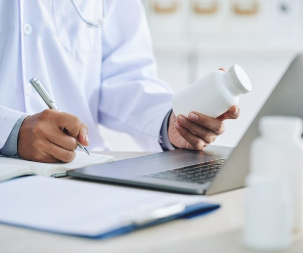 unrecognizable-female-doctor-with-laptop-holding-medication-writing-prescription unrecognizable-female-doctor-with-laptop-holding-medication-writing-prescription