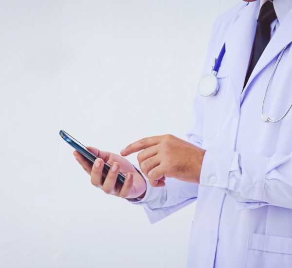 young doctor man wearing a white coat using a smartphone young doctor man wearing a white coat using a smartphone